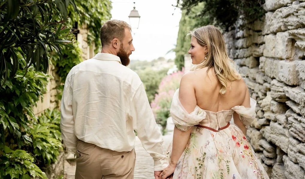 Couple walking hand in hand, looking at each other — woman in floral dress, Provence couple session