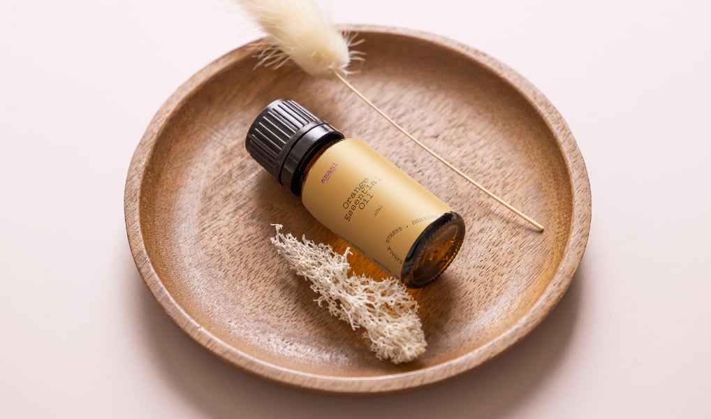 a bottle of essential oils on a plate with a feather feather