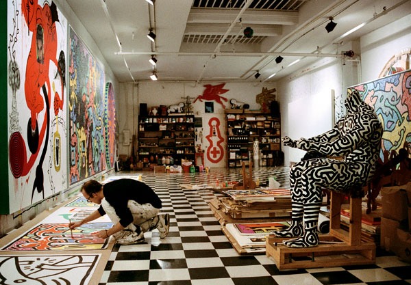 Ateliê vibrante de Keith Haring com paredes decoradas com grafite e arte pop.