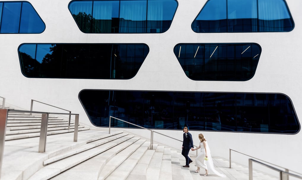 a bride and groom walking down stairs in front of a large building
