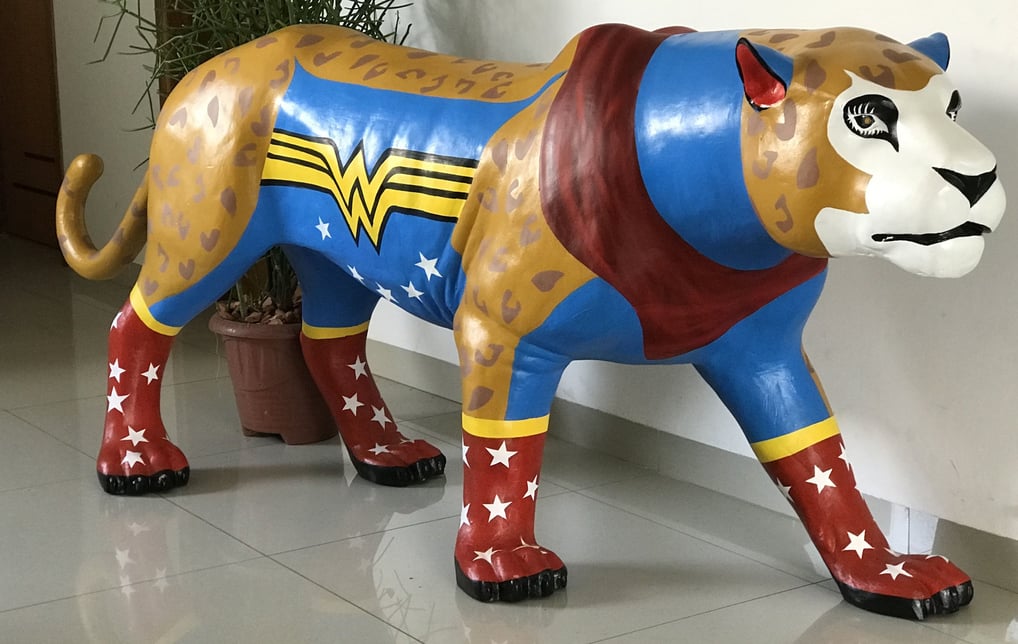 Detalhe da pintura da Onça Maravilha com padrões e cores vibrantes, alusões à Mulher Maravilha.