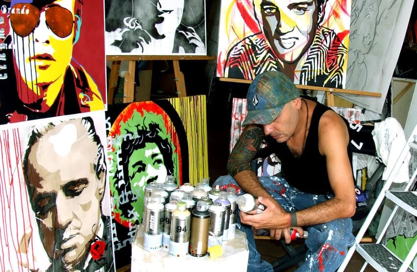 Sérgio Astral, em seu ateliê, com quadros em pop-art.
