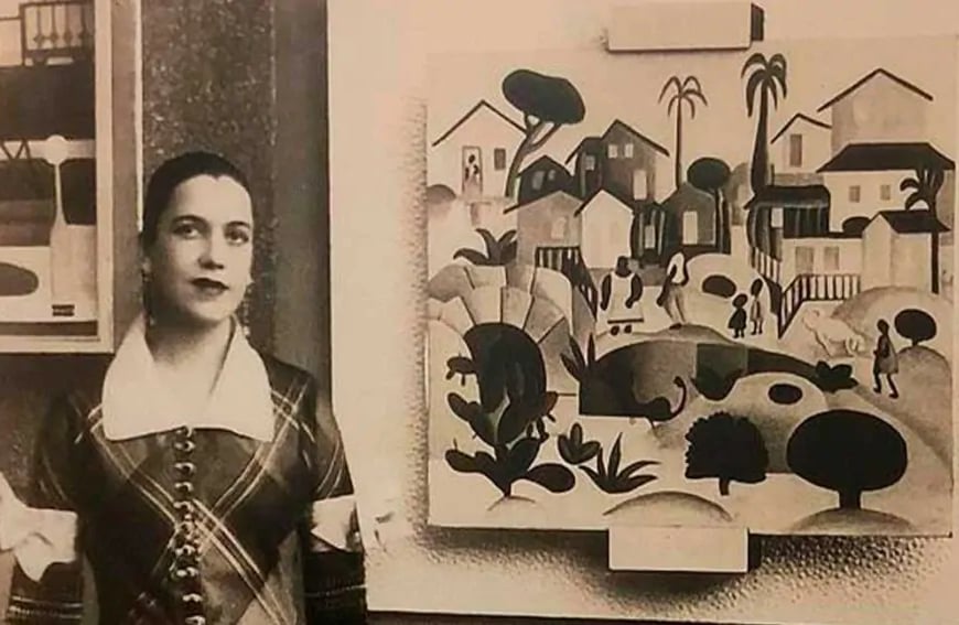 foto de Tarsila do Amaral, ao lado de uma quadro pintado por ela.