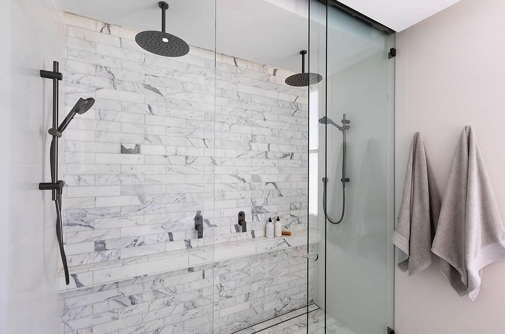 Modern en-suite bathroom featuring a glass-enclosed shower cubicle with dual rain shower