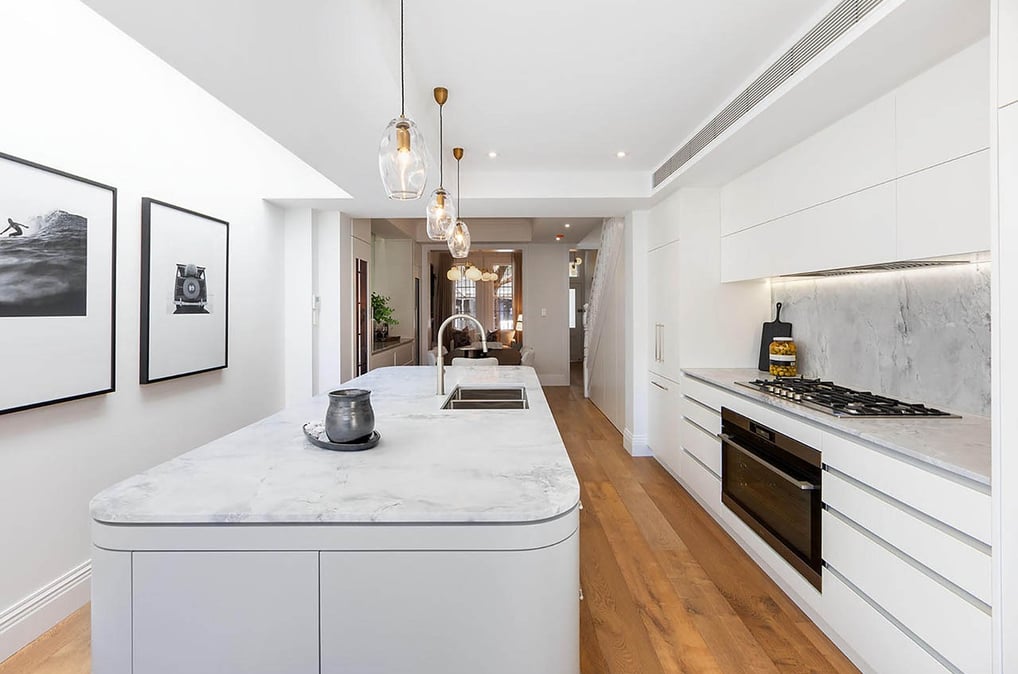 Modern kitchen interior design with central island, white cabinetry, integrated appliances