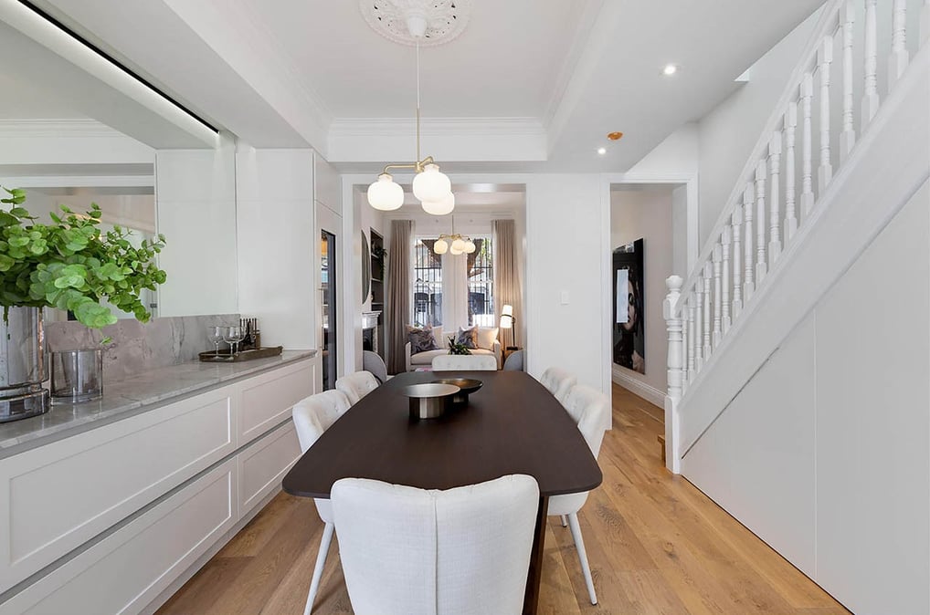 Dining room beside traditional Victorian timber staircase with central pendant light, wall mirror
