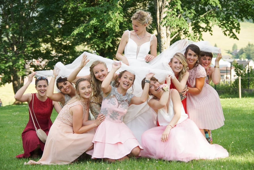 photo de mariée avec ses demoiselles d'honneur souriantes jouant avec et sous sa robe