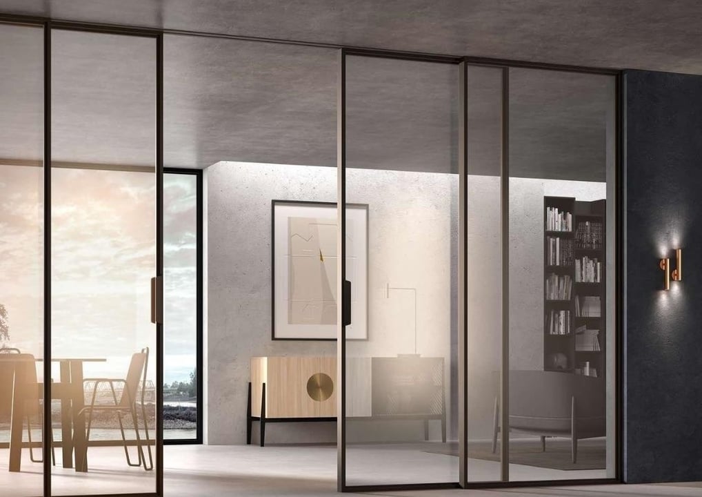 Cerramiento de cristal corredero con marcos oscuros en comedor de diseño minimalista