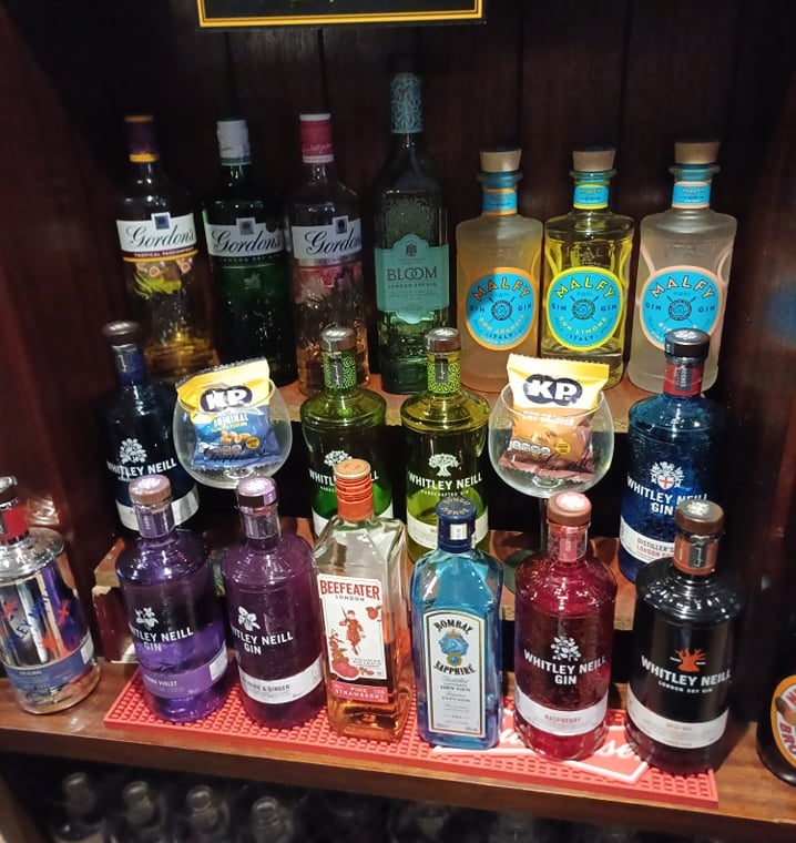 a shelf of gin bottles and liquor bottles