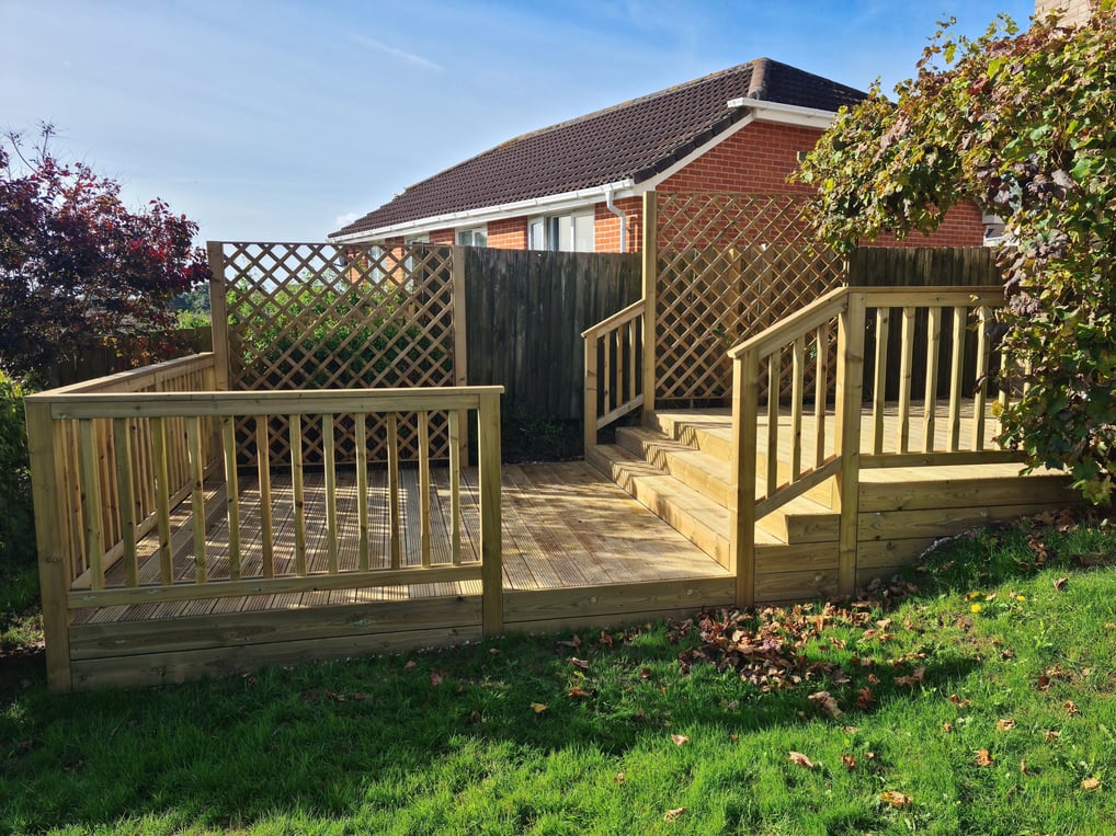 Garden with a timber deck made on two levels, including steps, balustrades and trellises.