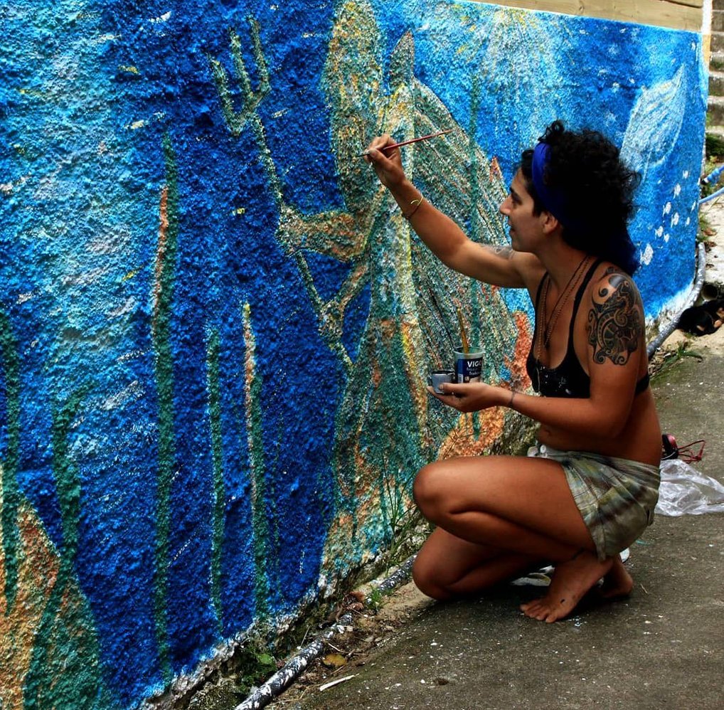 Naía peignant une peinture murale représentant un fond marin avec poseidon, ue baleine