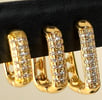 a pair of gold toned earrings with diamond set in the middle