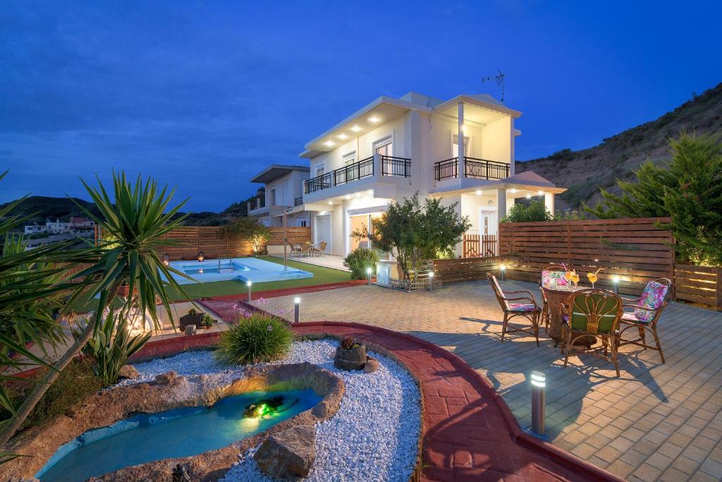 Luxury modern villa at dusk featuring a swimming pool, landscaped garden, and outdoor patio dining area.