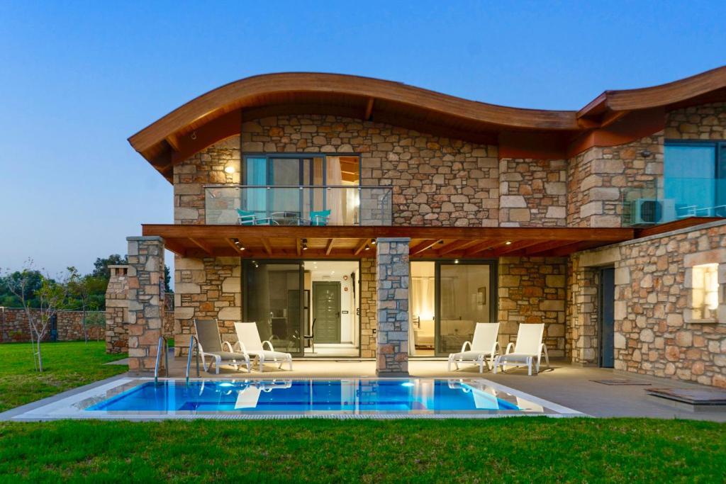 Luxury stone villa with a private swimming pool and modern curved roof architecture at dusk.
