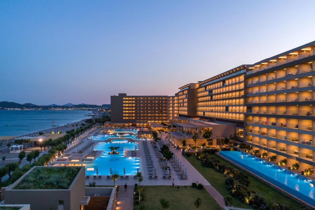 Luxury beach resort at dusk featuring illuminated swimming pools and modern oceanfront architecture.