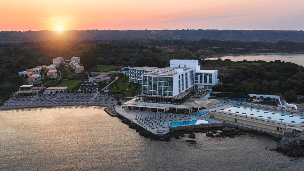 Aerial view of a luxury beachfront resort with a swimming pool at sunset over the Mediterranean coast.