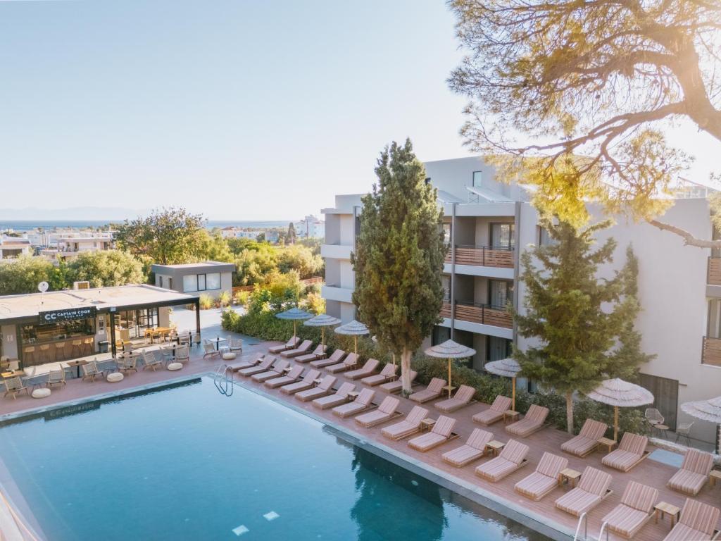 Luxury hotel swimming pool with lounge chairs and straw umbrellas at a Greek seaside resort.