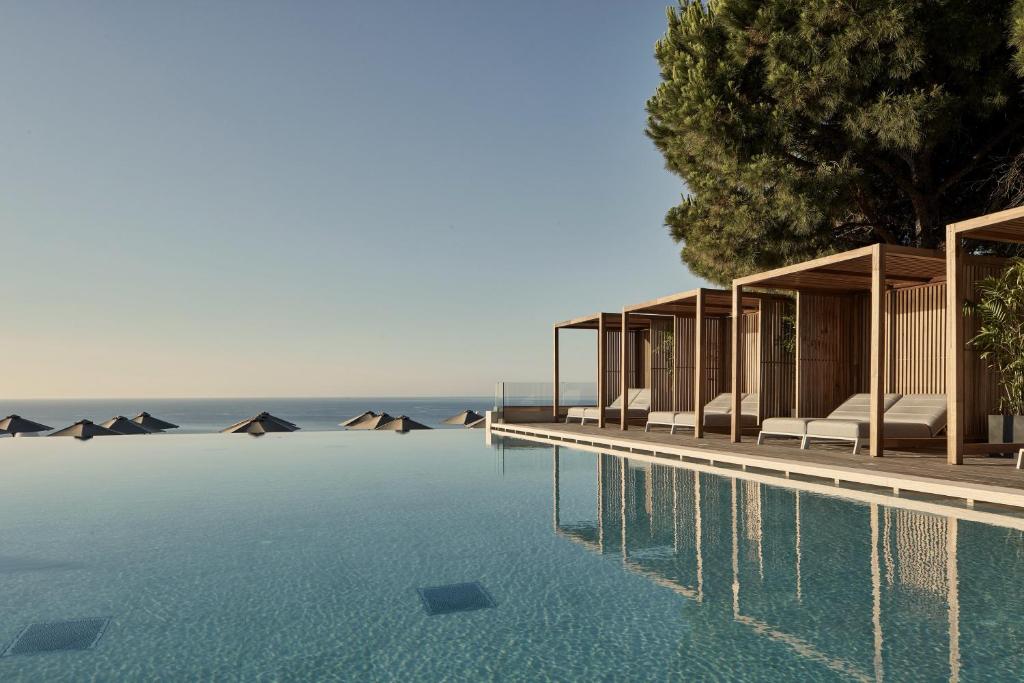 Luxurious infinity pool overlooking the Aegean Sea with private shaded cabanas at a serene resort, perfect for a relaxing