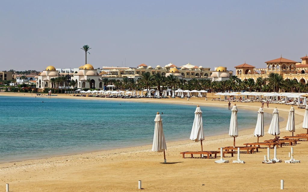 Luxury Sahl Hasheesh beach resort in Egypt featuring white umbrellas on a sandy shore.