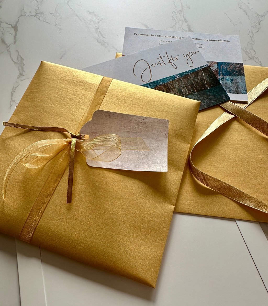 gift wrapped package with gold paper and handmade collage paper tag