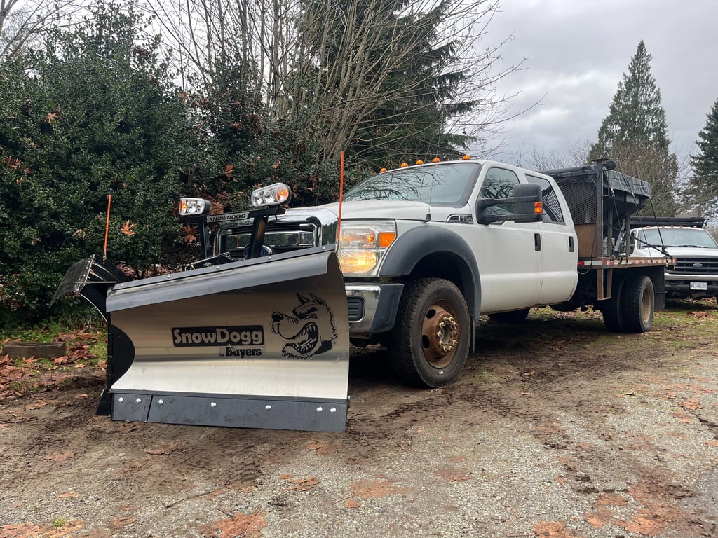 a white truck with a silver V plow blade 
