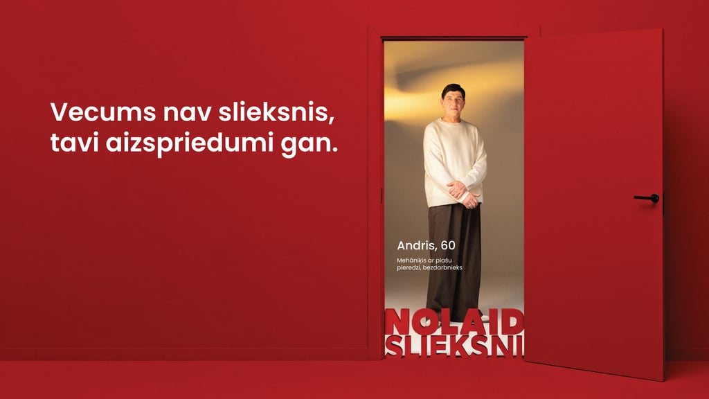 Gados vecāks vīrietis stāv atvērtās durvīs. Teksts: Vecums nav slieksnis, tavi aizspriedumi gan.