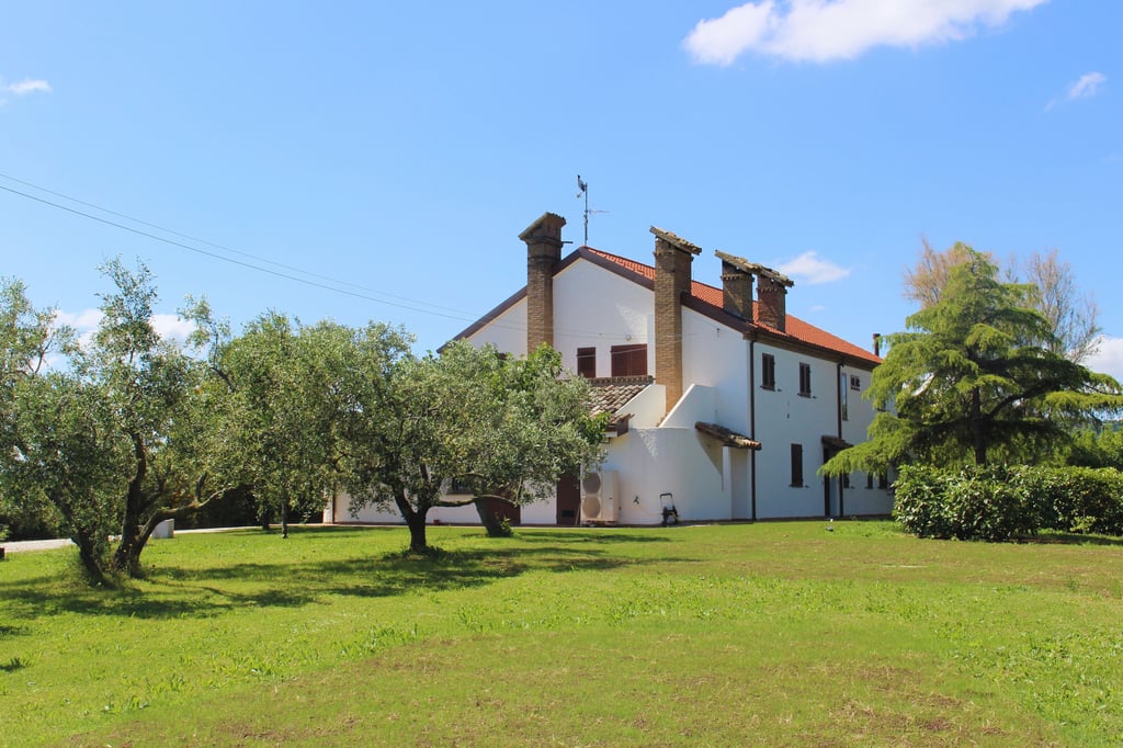 Facciata esterna della casa colonica del B&B La Collina e il Mare immersa nel verde a Saludecio.