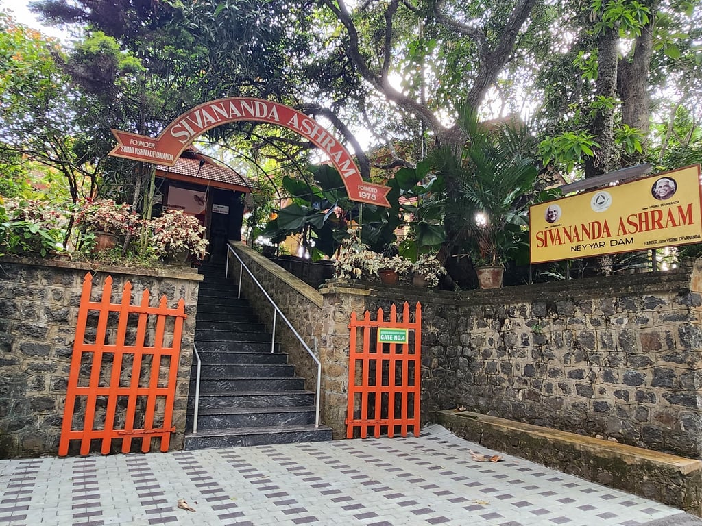 The stone entrance and orange gates of Sivananda Ashram Neyyar Dam yoga retreat in Kerala, India.