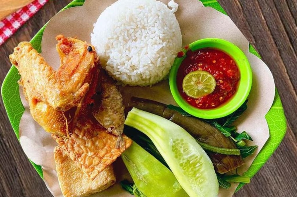 Indonesian Ayam Goreng Lalapan with fried chicken, white rice, sambal, and fresh vegetables.