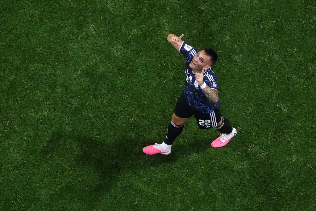 Argentina soccer player Lautaro Martinez celebrates a goal on the green field during a match.