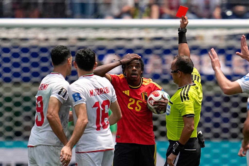 A soccer referee shows a red card to a shocked Belgium player during an international football match.
