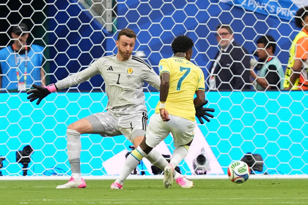 Brazil's Vinicius Junior dribbles past the Scotland goalkeeper during a football match.
