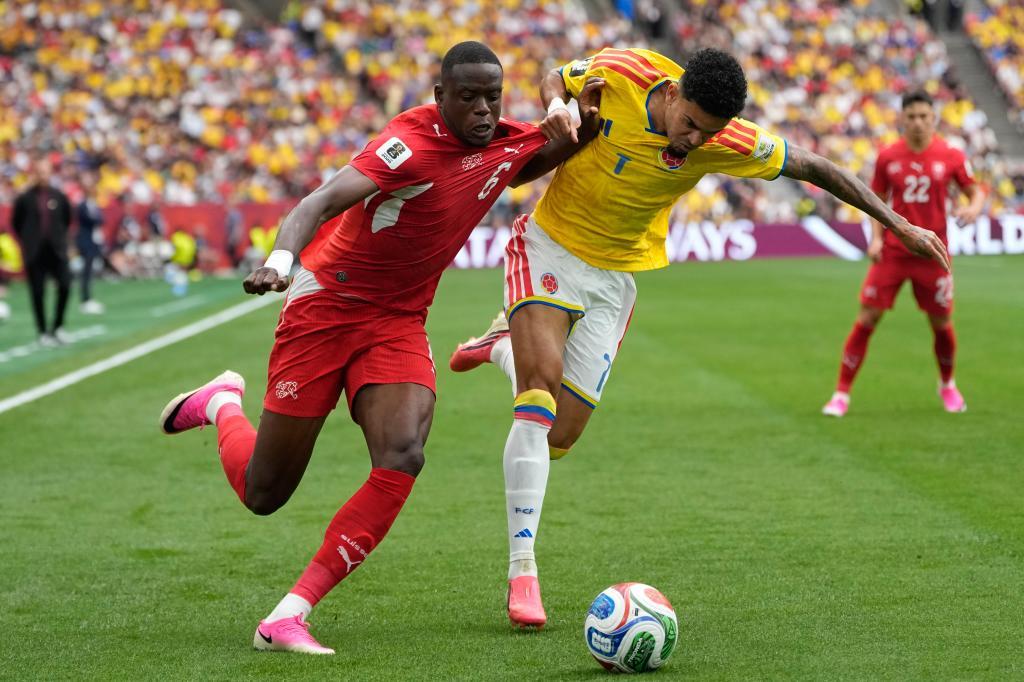 Two professional soccer players in red and yellow jerseys competing for a ball during an international match.