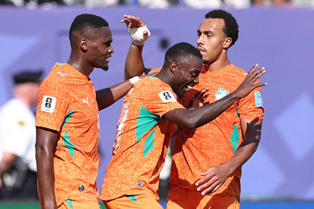 Ivory Coast national football team players celebrating a goal in orange kits.
