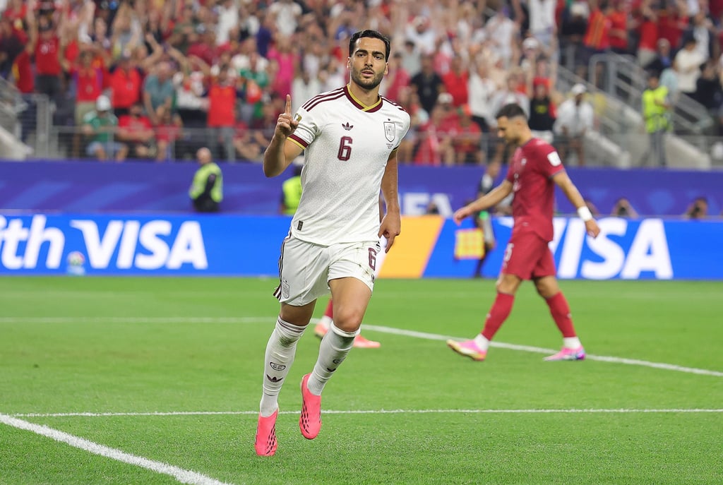Spain's Mikel Merino celebrates a goal in his white national team jersey during a soccer match.
