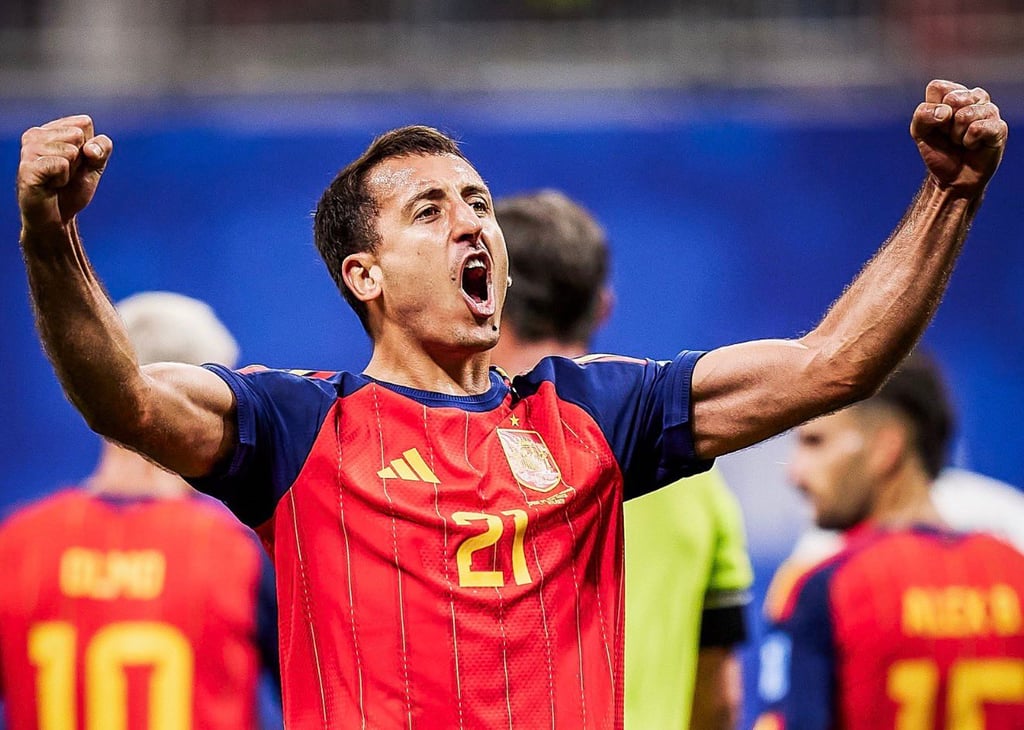 Spain soccer player Mikel Oyarzabal celebrates a goal with arms raised during a match.
