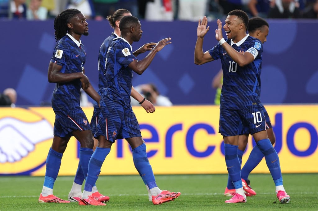 Kylian Mbappe celebrates with France teammates on the pitch during a professional football match.
