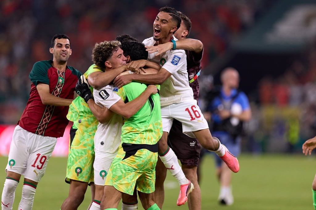 Morocco national football team players celebrating a goal victory together on the soccer field.