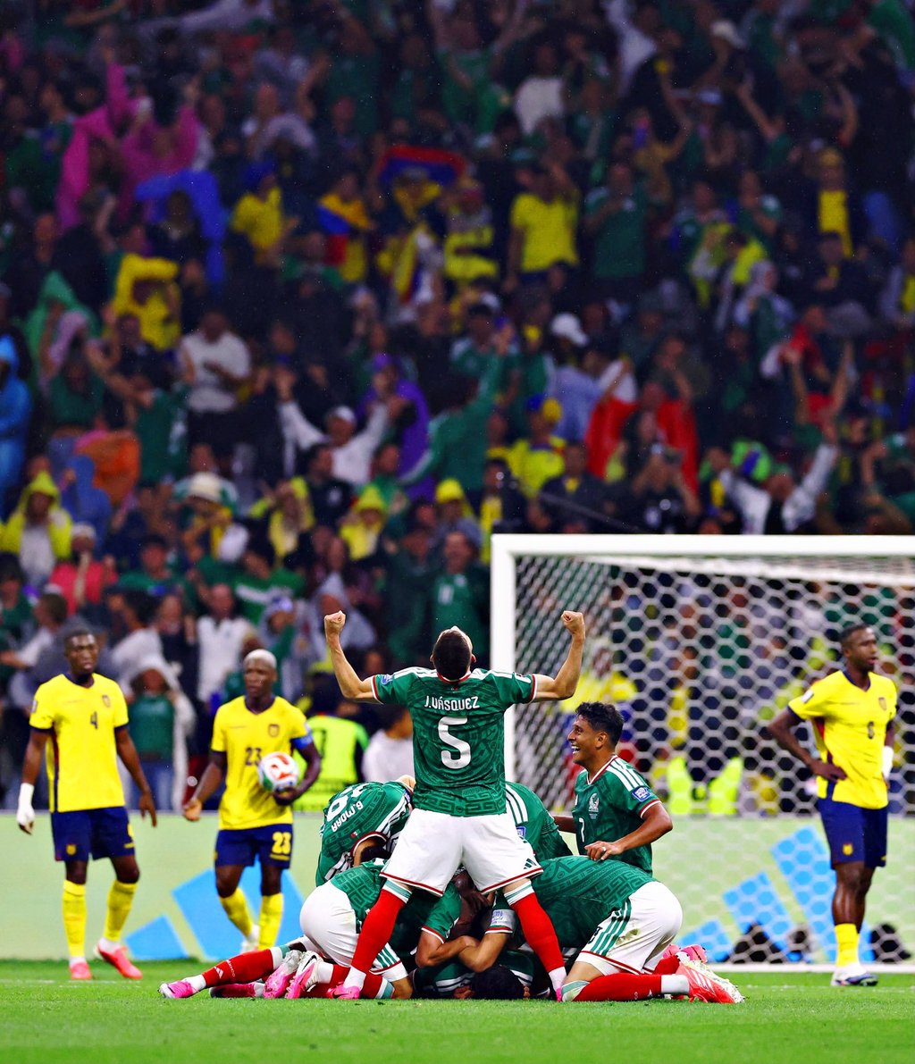 Mexico national team soccer players celebrate a goal on the field during a match against Ecuador.
