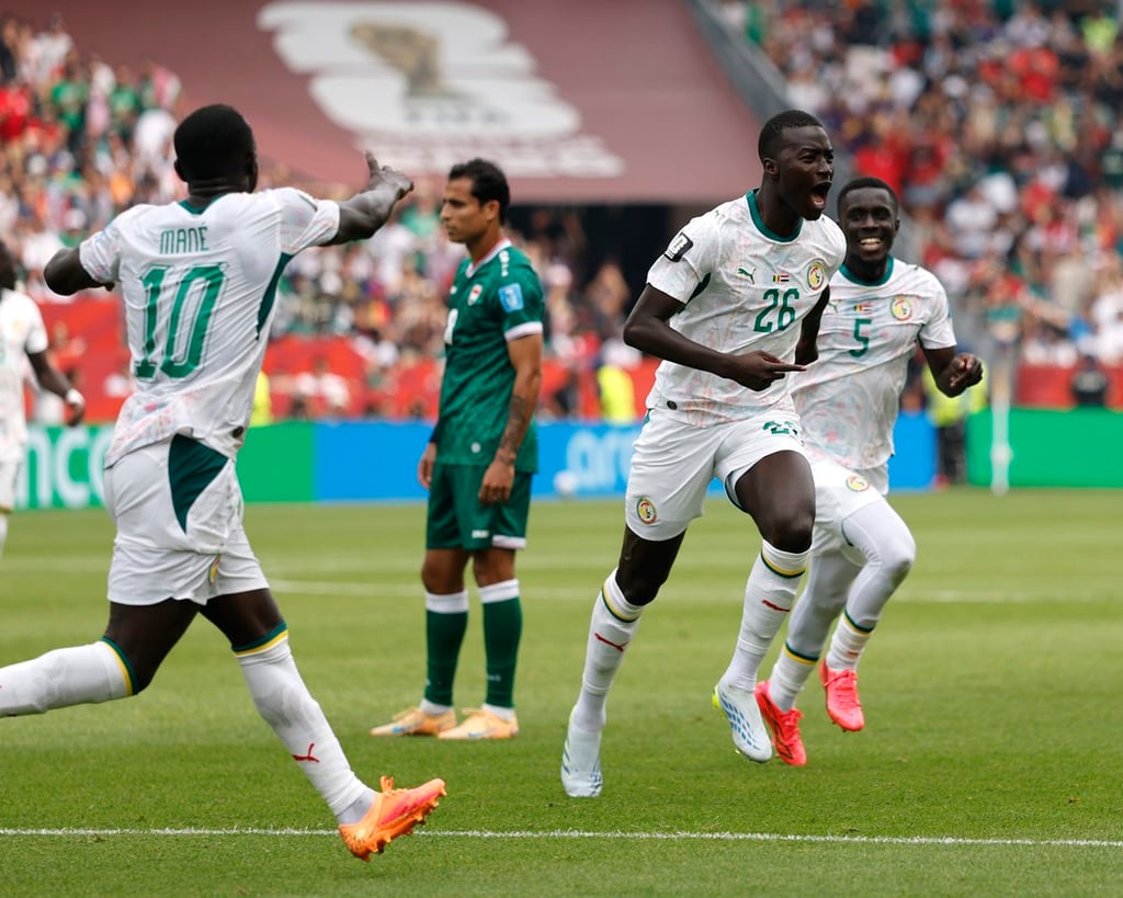 Senegal national football team players celebrating a goal during a World Cup match on a grass field.