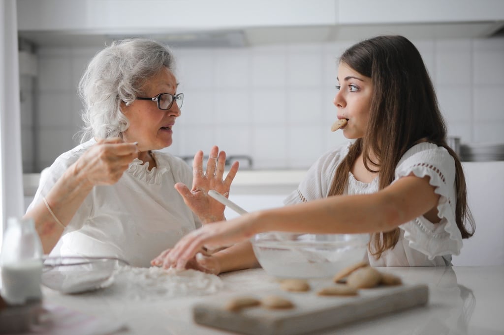 Grandmother and granddaughter baking homemade cookies together in a bright kitchen.