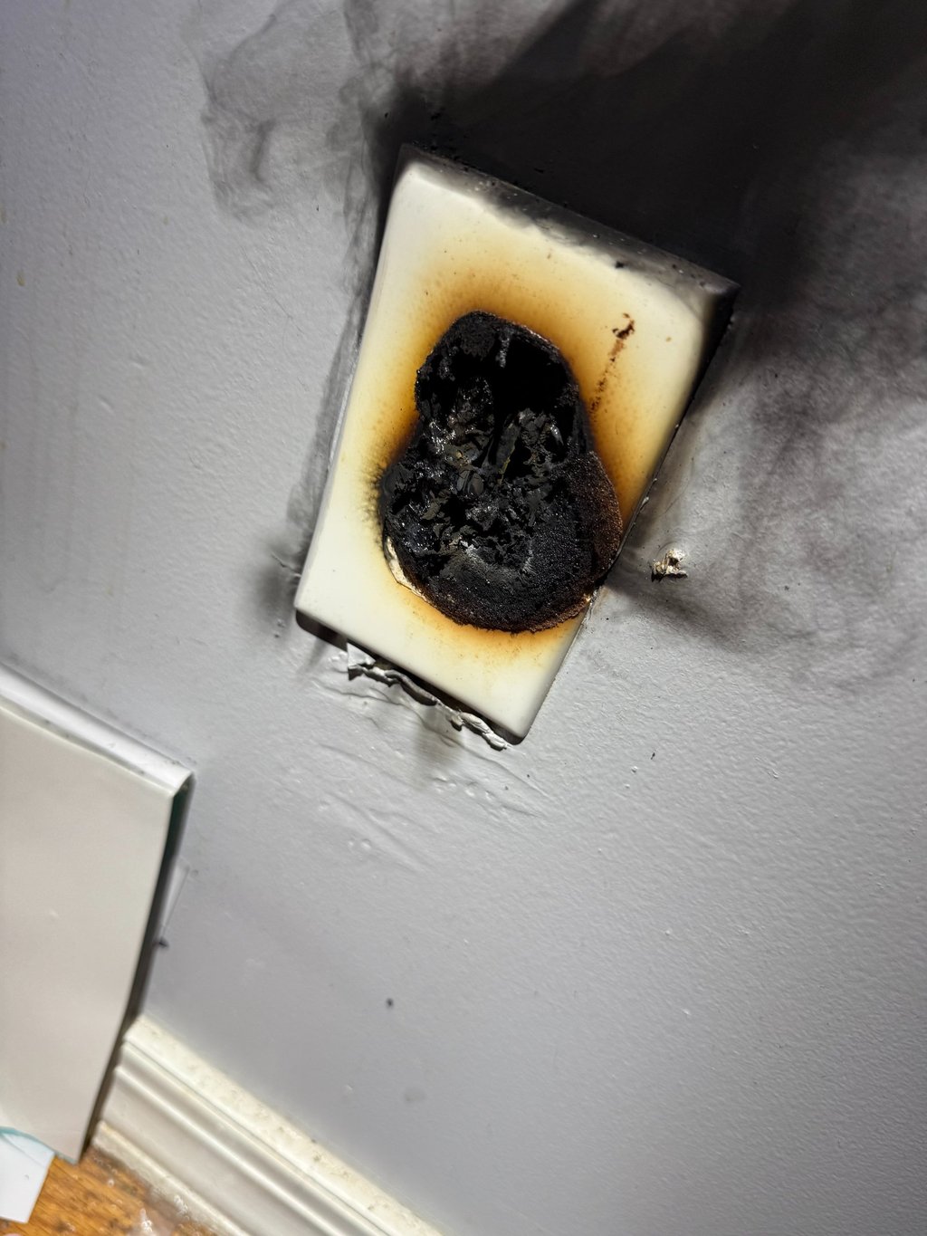 Burned electrical outlet plug showing heat damage and charring