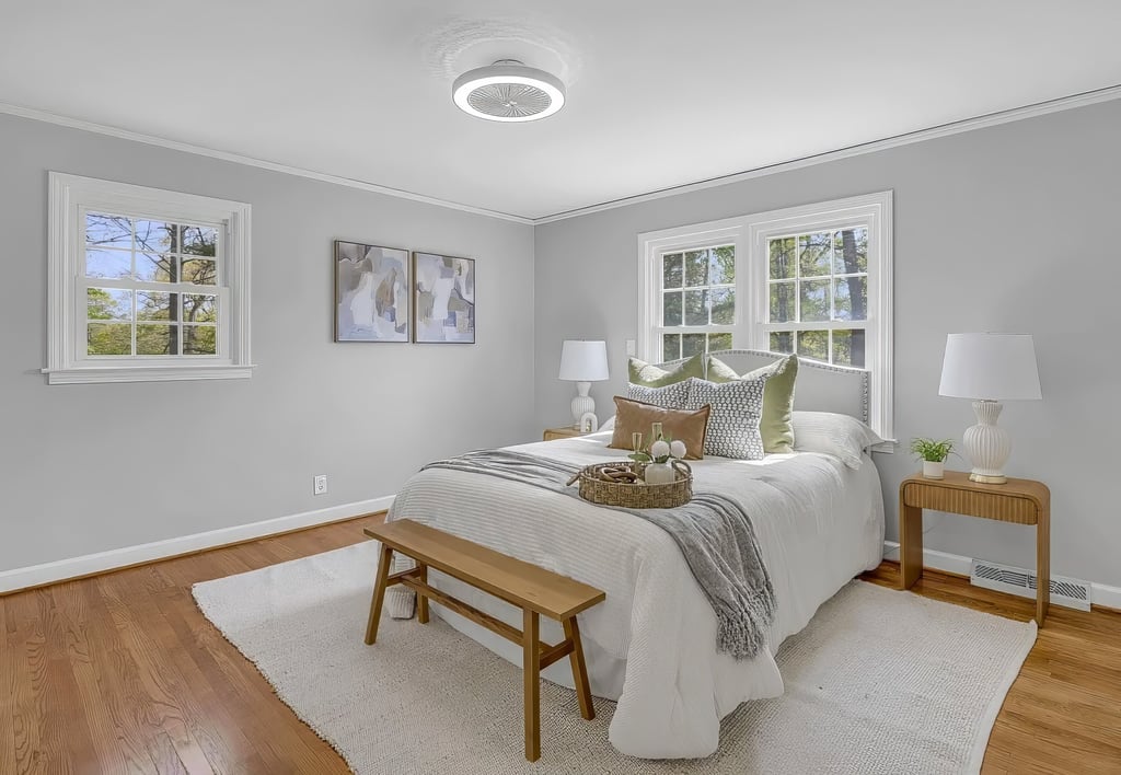 Staged primary bedroom in Upstate SC with a layered queen bed, wood bench, neutral rug, and natural 