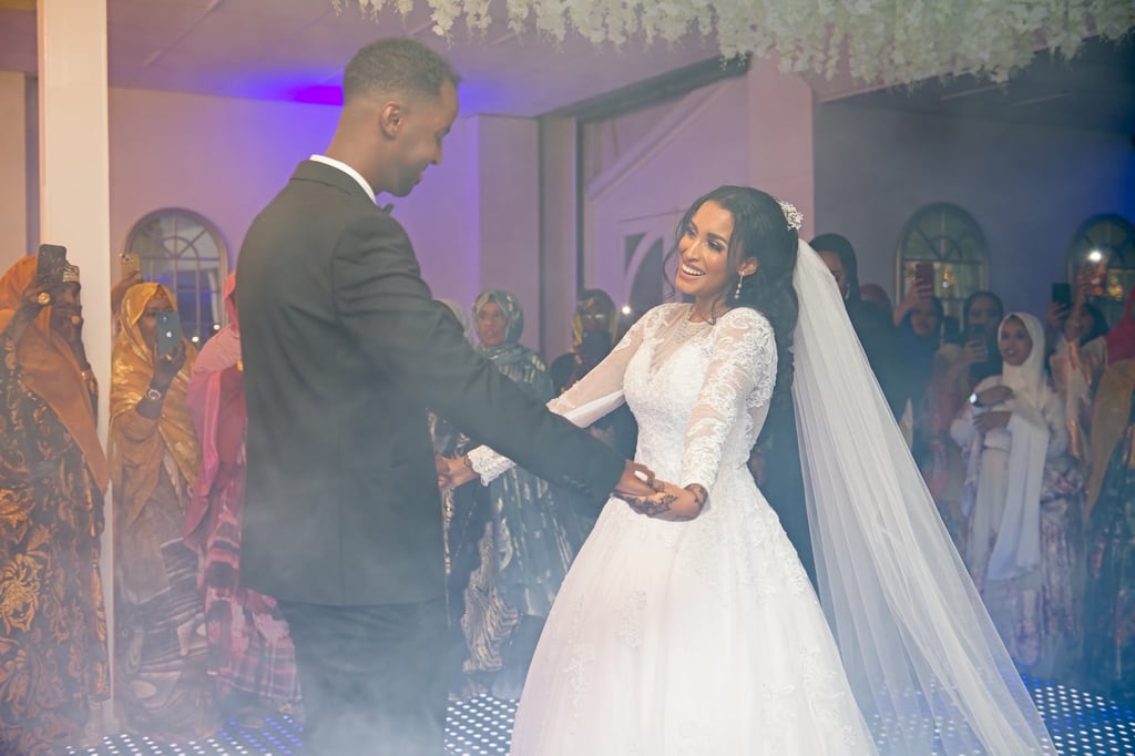 Bride in white wedding dress & groom in black suit dancing and smiling