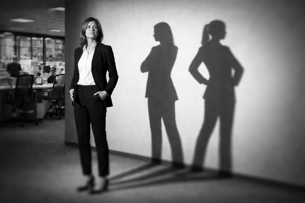 Image of a woman standing in an office setting projecting a double shadow on the wall