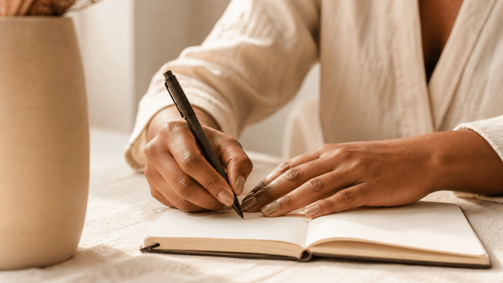 Close up of a woman's hands writing in a journal financial journaling and money reflection