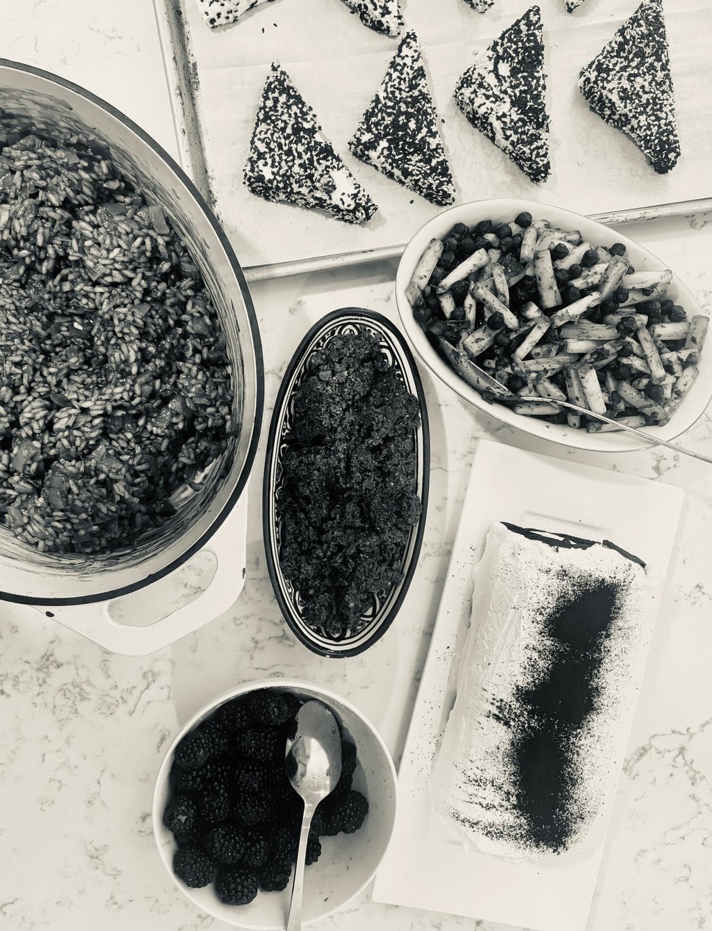 Flat lay of gourmet dishes including risotto, salad, and appetizers served on a marble countertop.