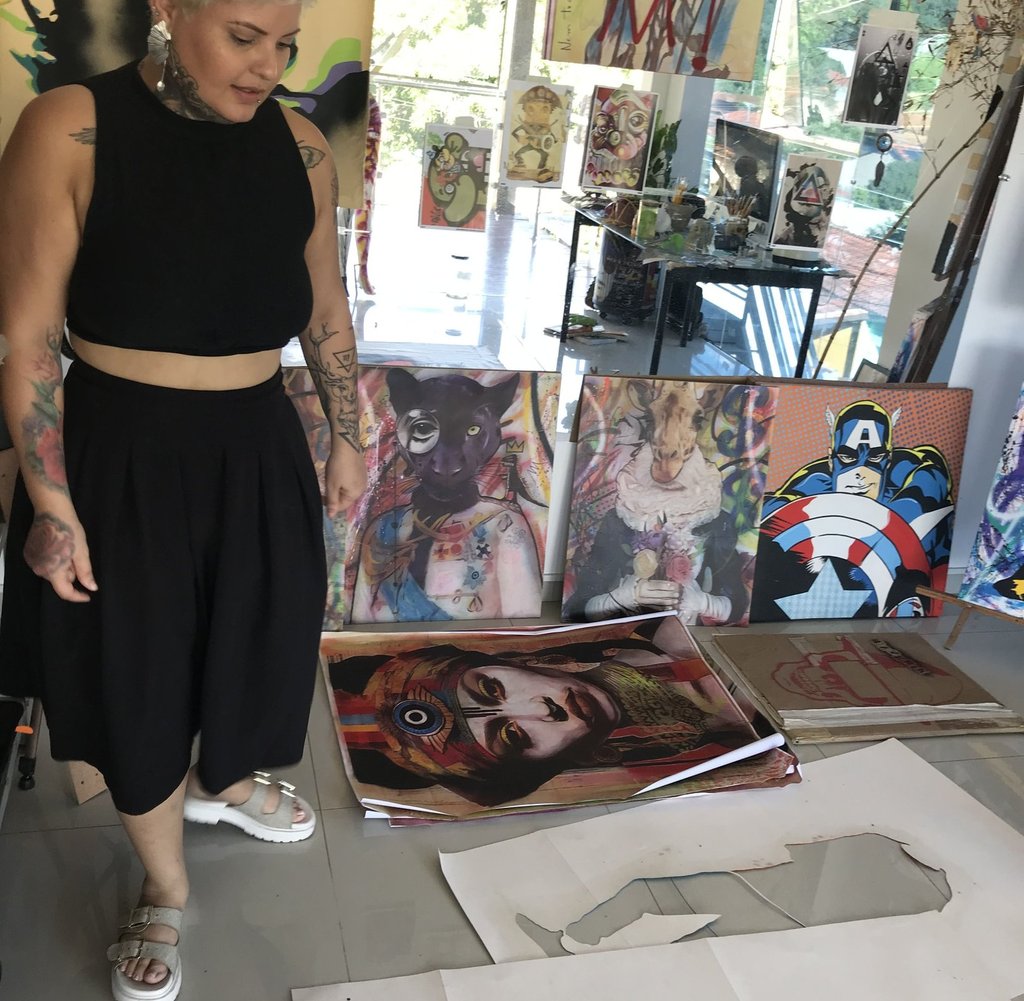 Amanda Amorim aplica spray em uma tela, criando uma obra com temas indígenas.