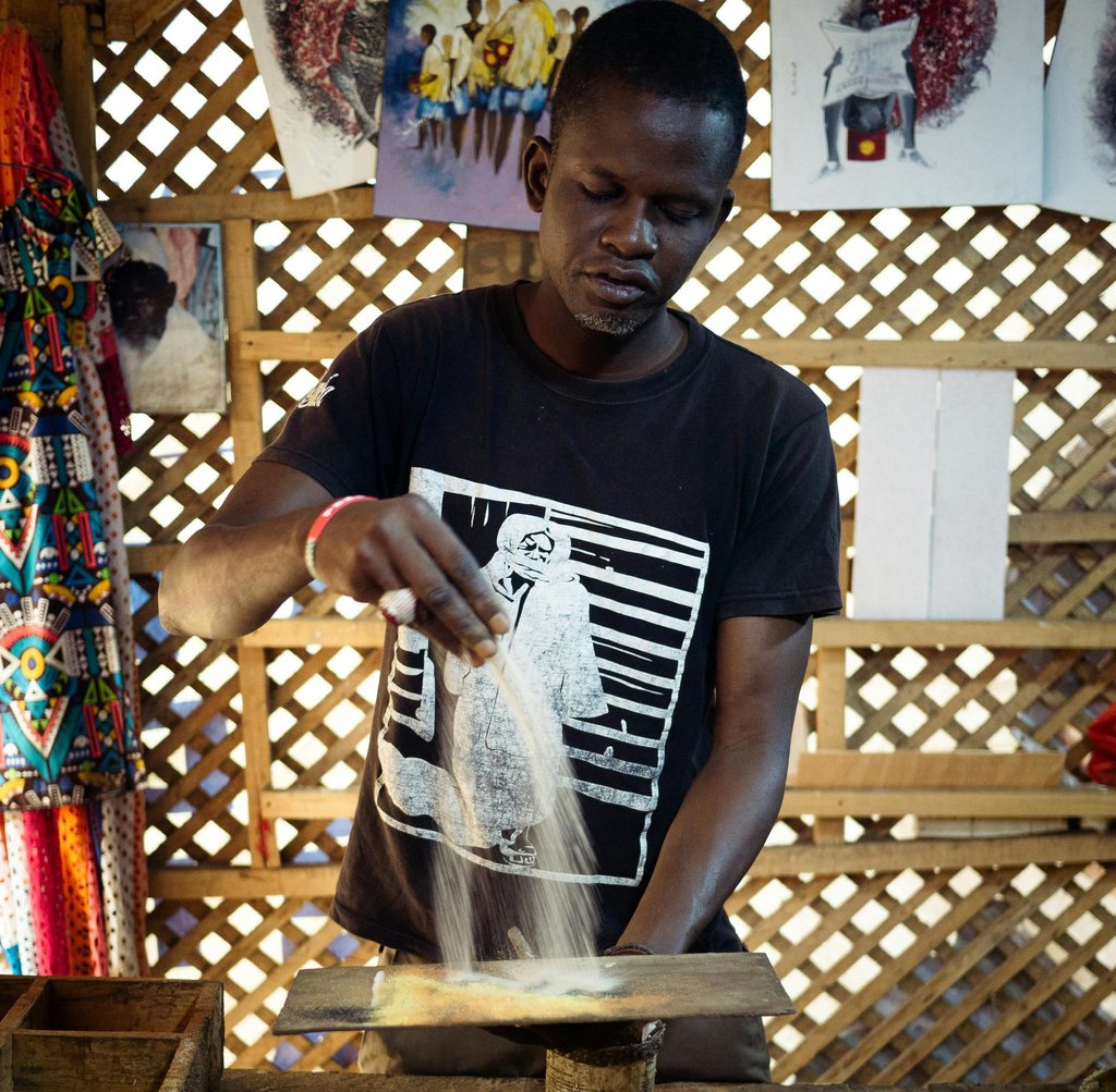 homme faisant de la peinture de sable au sénégal