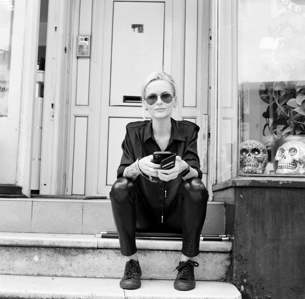 Woman sits outside her hair salon taking a break